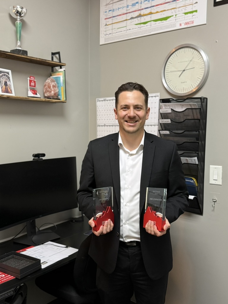 Jake Johnston holding his two Spirit Awards at the Royal LePage Elite West office